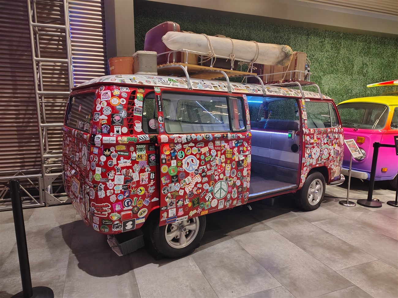 A red VW bus completely covered in colorful stickers