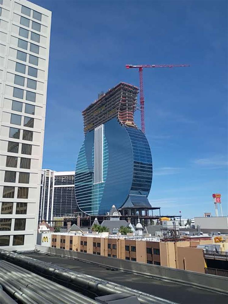 A curved glass skyscraper under construction with a tower crane