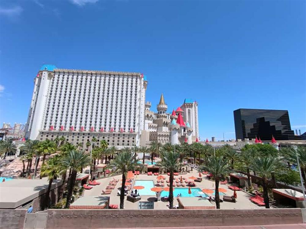 Excalibur's pool deck with palm trees and orange umbrellas