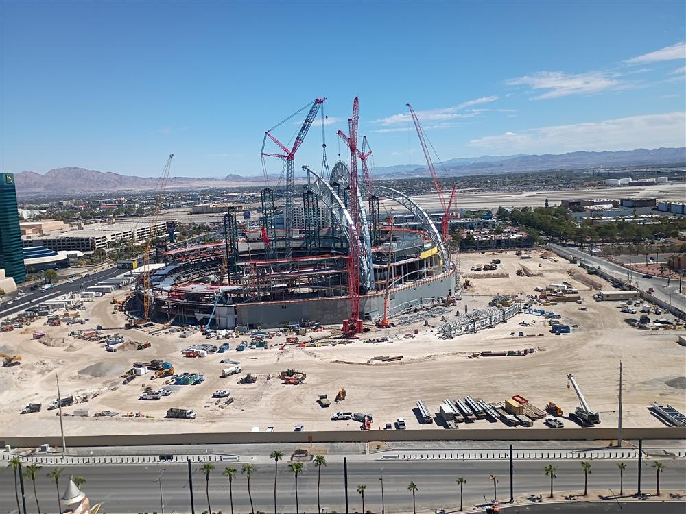 A stadium under construction with tower cranes against the desert sky