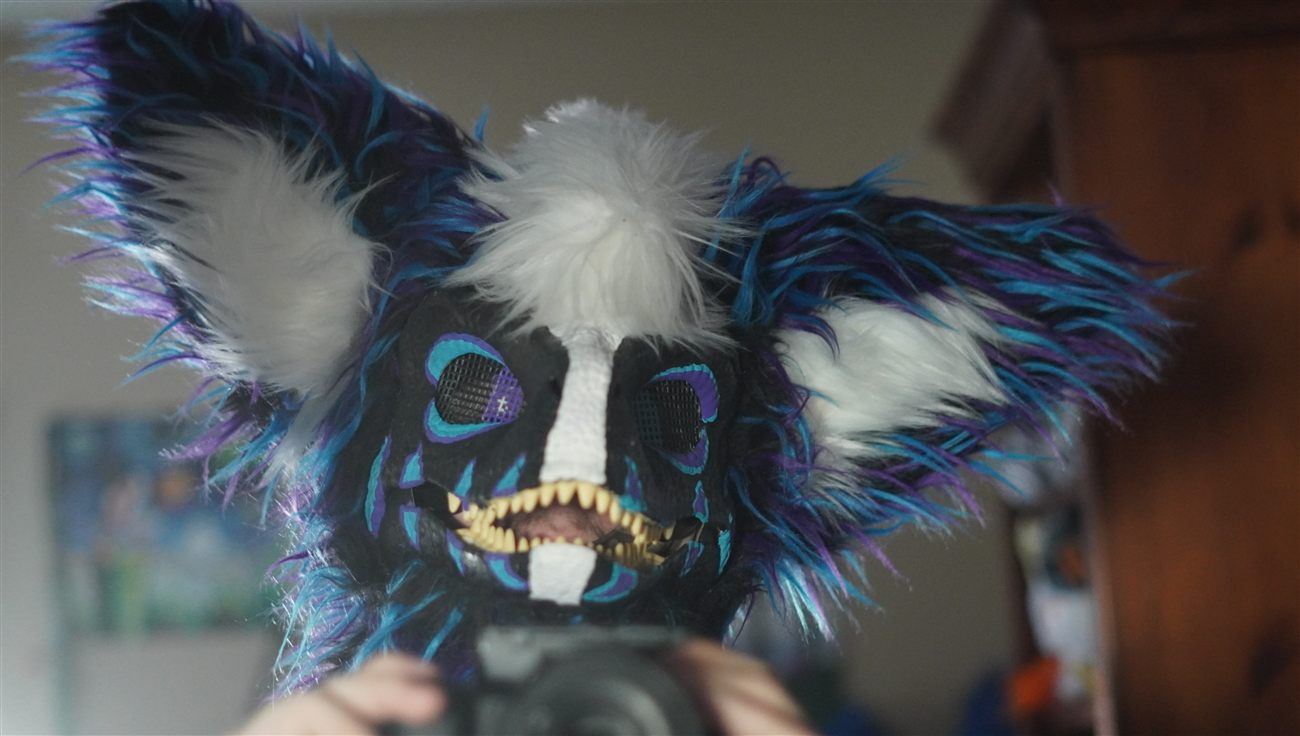 Close-up of the dino fursuit head's fangs and mesh eyes