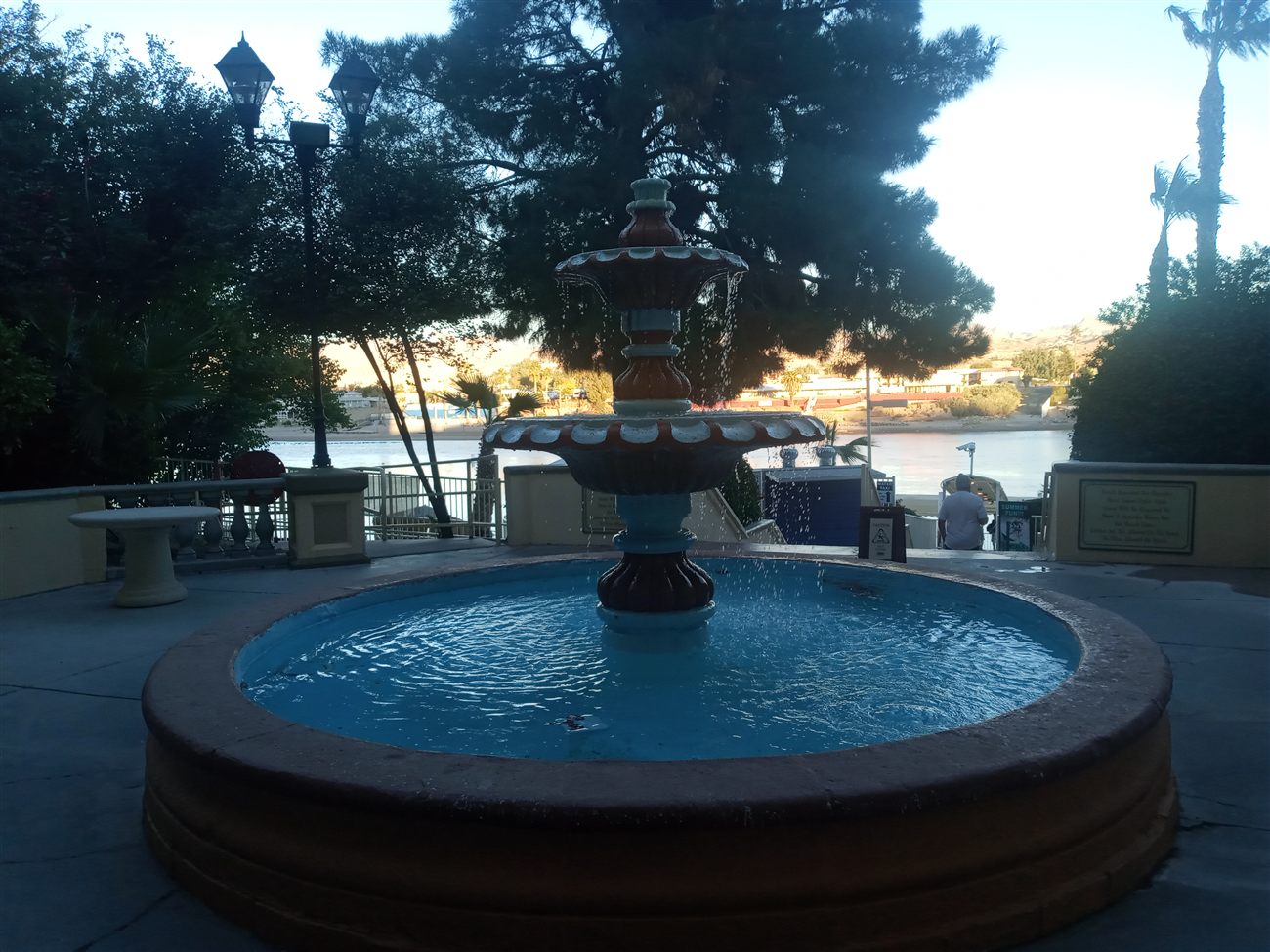A stone fountain with the Colorado River and mountains behind it at dusk