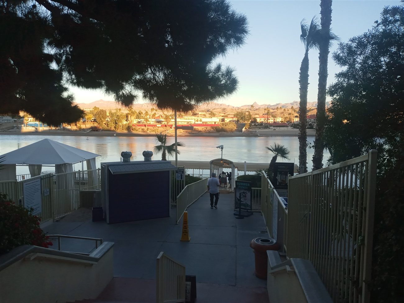 A riverside walkway leading to a water taxi dock at golden hour
